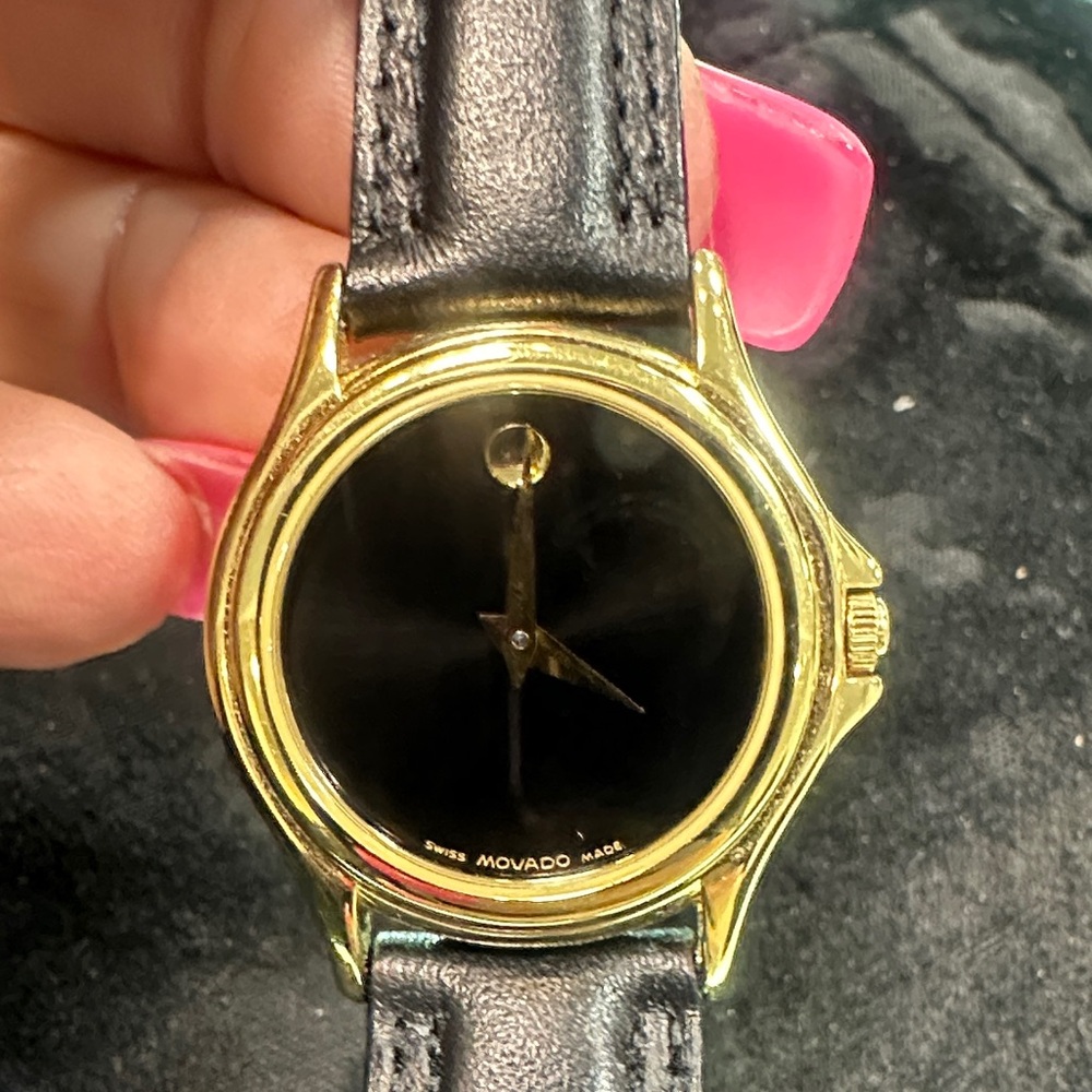 Movado Gold Tone Case with Black Dial and Black Leather Strap.  Quartz movement